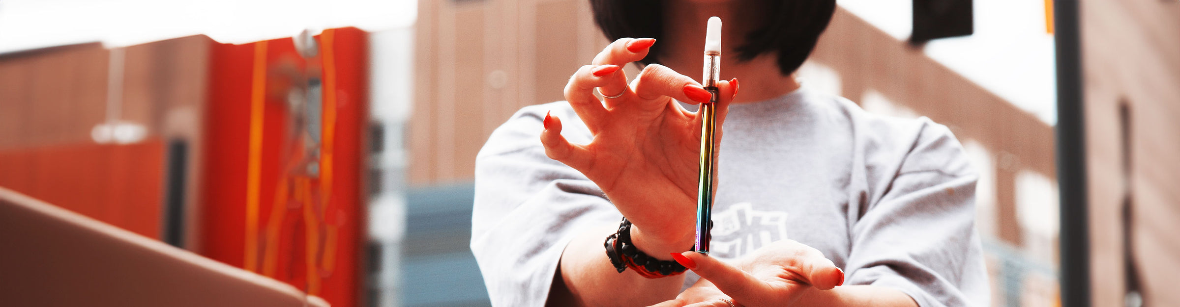 Woman holding Exxus Vape in front of warehouse