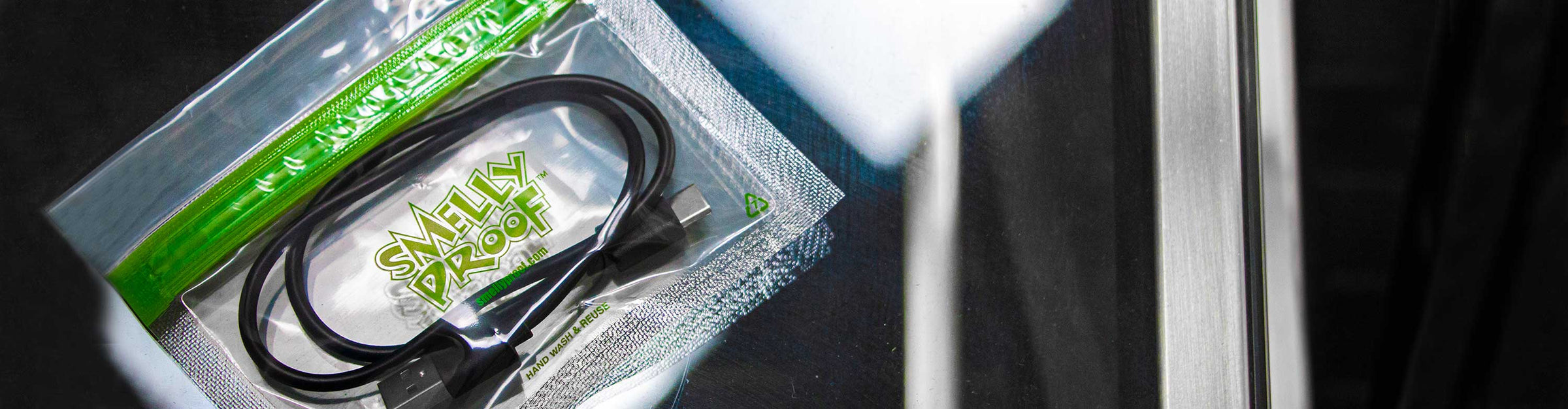 Small Sized Smelly Proof bag with USB Cable inside laying on glass table in normal lighting